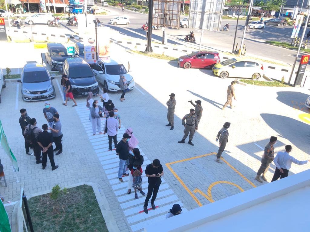Suasana pelanggan McD Kendari sedang mengantre untuk masuk ke dalam dengan tetap jaga jarak. 