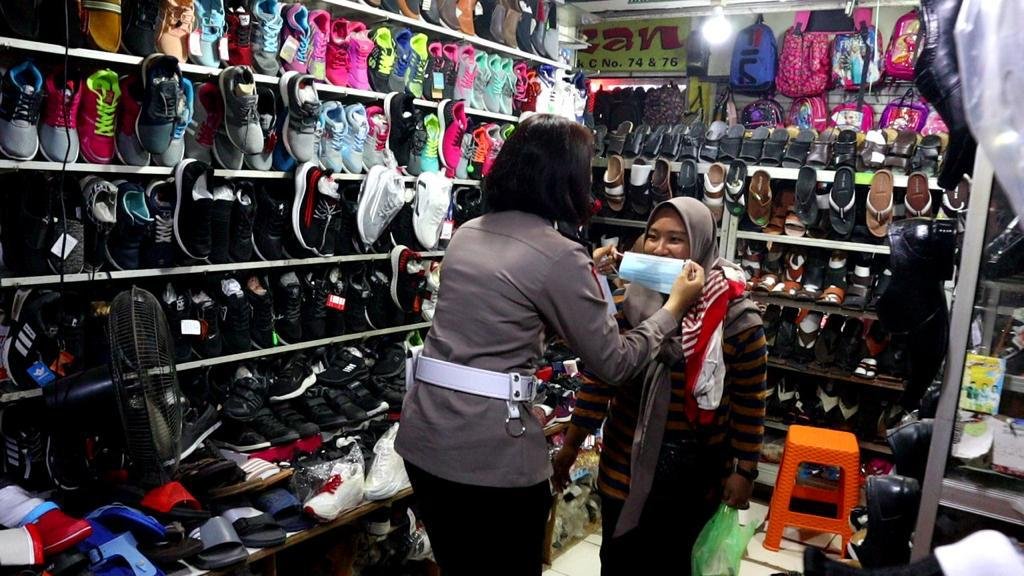 Salah seorang personel Polres Kendari memasangkan masker kepada pengunjung yang tidak mengenakan masker. Foto: Polres Kendari. (7/5/2021).