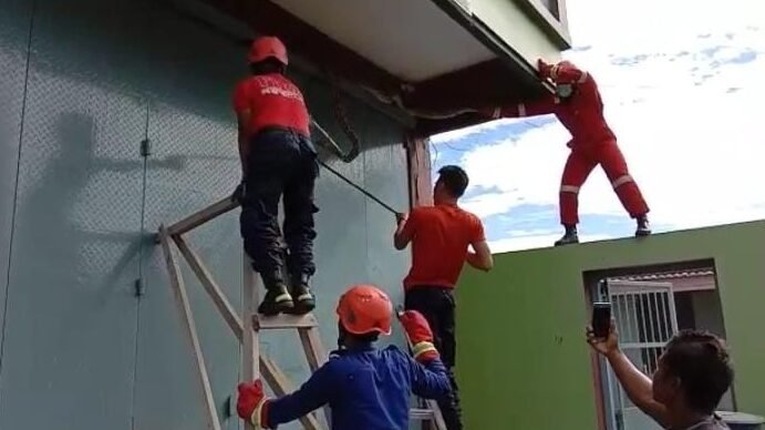 Petugas Dinas Kebakaran Baubau mengevakuasi ular piton di atas pintu ruko di Kelurahan Bone Bone.