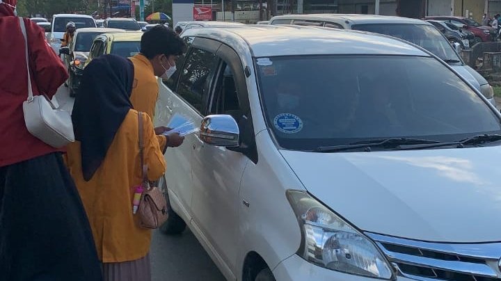 Mahasiswa farmasi membagikan masker kepada pengendara di Kendari.