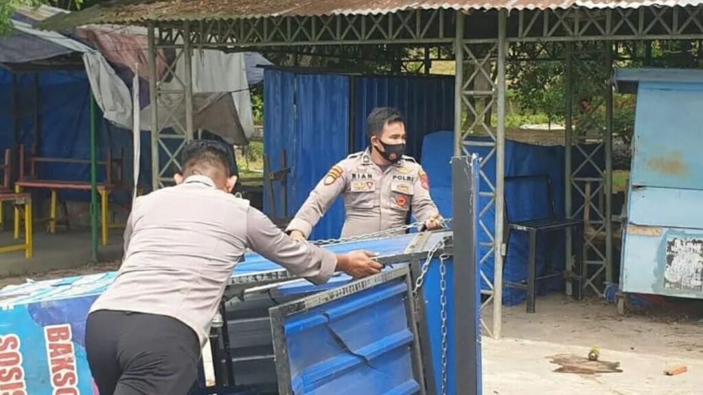 Personel kepolisian merapikan jualan warga di Kendari Beach.