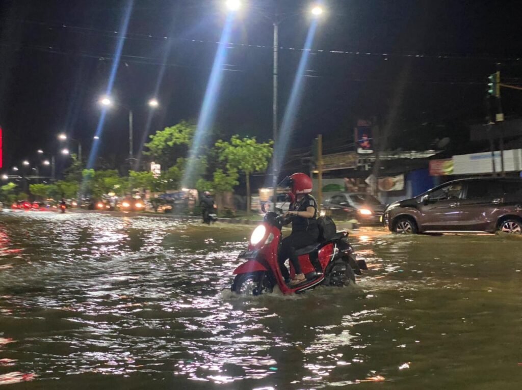 Pengendara motor melintasi banjir di Eks MTQ, Kota Kendari.
