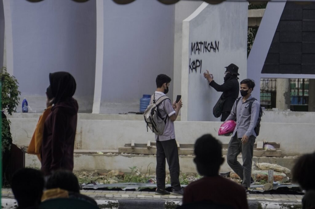 Massa aksi mencoret-coret tembok papan nama Kantor Wali Kota Kendari. 