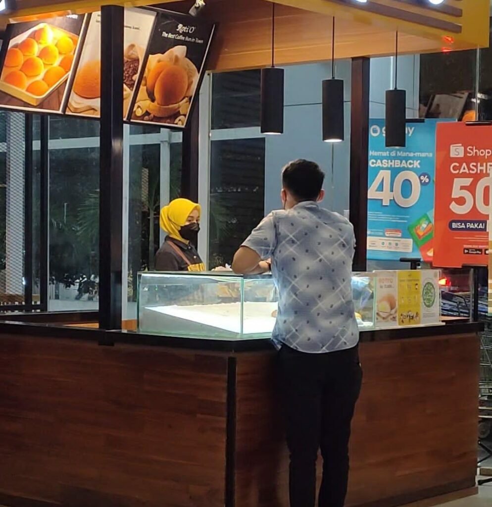 Henok Paningo saat memberikan tulisan berupa ucapan dukungan dan semangat kepada salah satu karyawan toko roti di Kendari.