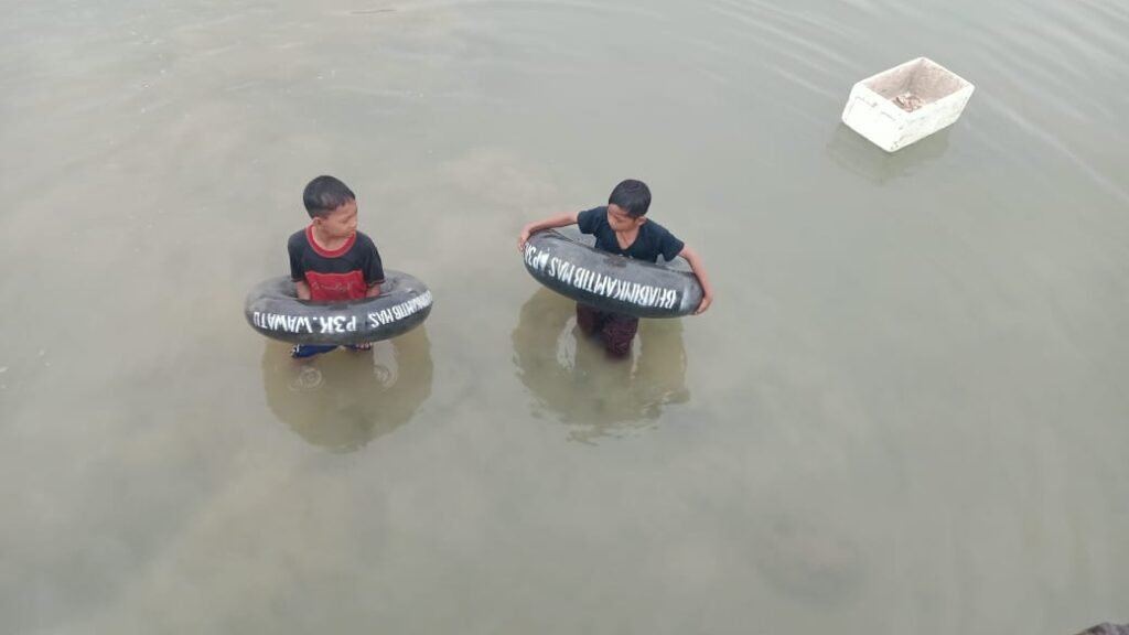 Anak-anak yang sedang mandi-mandi menggunakan ban bekas yang dibagikan oleh Bripka Ifaruddin.
