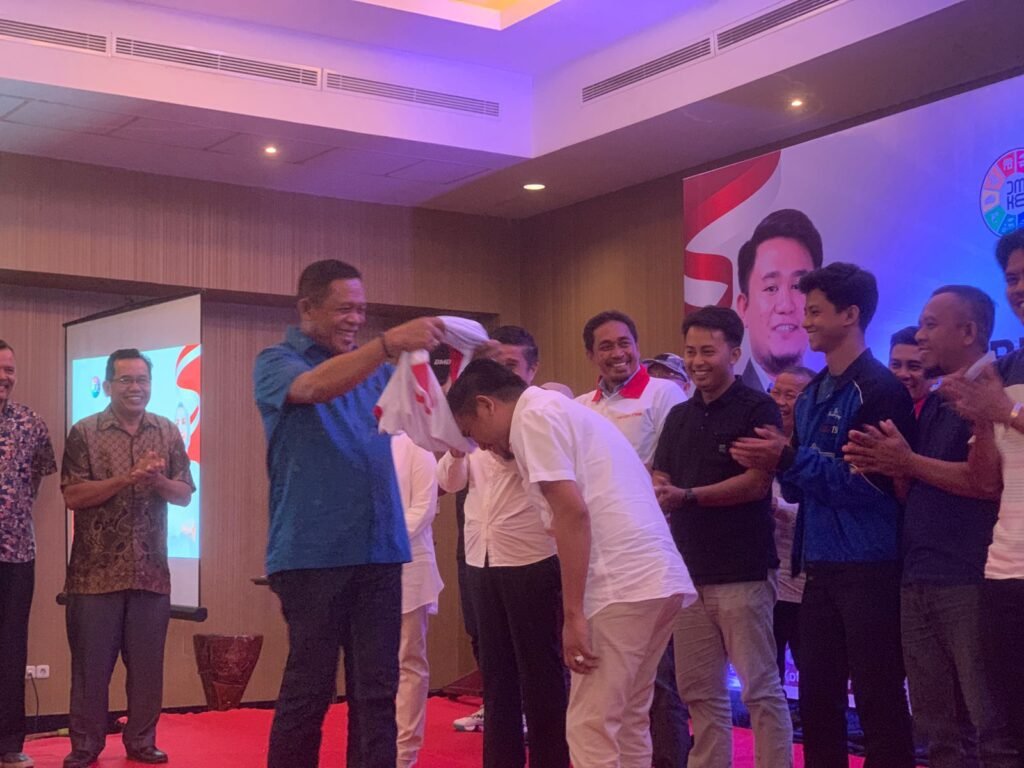 Penyematan baju oleh anggota Komisi II DPR RI, Ir. Hugua kepada Ketua Tim Brigade Hj. Gunartin, Irwanto sebagai simbol pengukuhan.