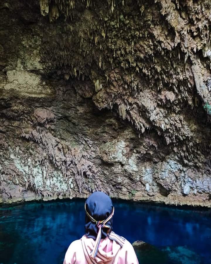 Seorang wisatawan mengambil foto berlatar stalaktit dan air di kolam Gua Koo.