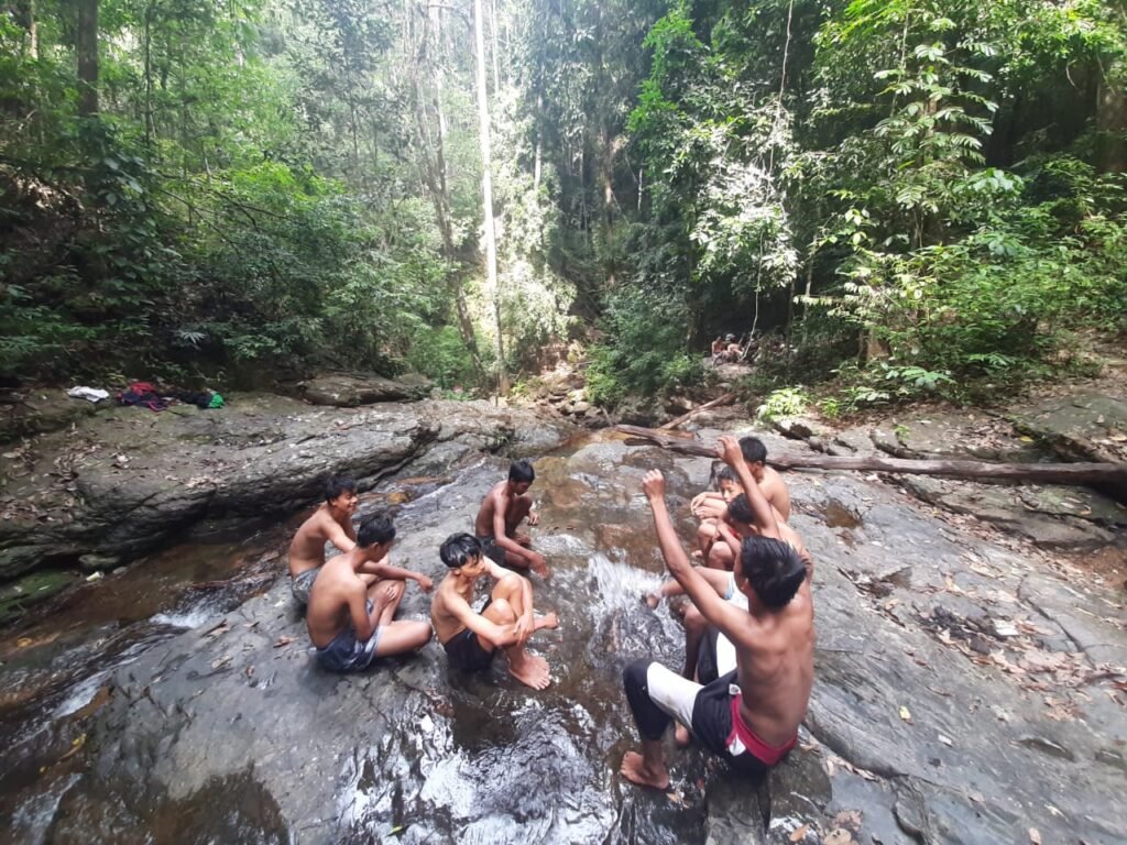 Wisatawan tengah bersantai sambil menikmati keindahan Air Terjun Waworaha dari atas ketinggian.