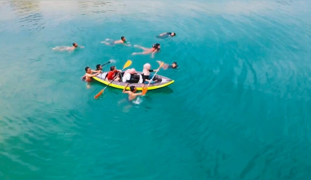 Wisatawan berenang menggunakan kano untuk menikmati keindahan Telaga Biru Oheo Konut.