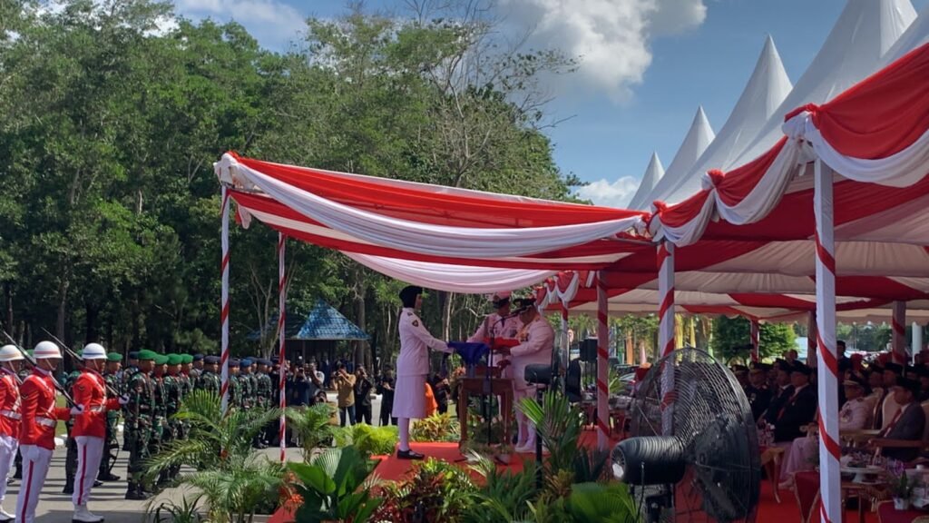 Gubernur Sultra, Ali Mazi saat menyerahkan bendera kepada pembawa baki untuk dikibarkan.