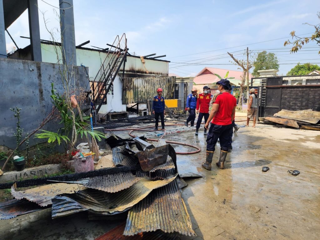 Tim Damkar Kendari memadamkan rumah indekos milik mantan Bupati Butur yang terbakar.