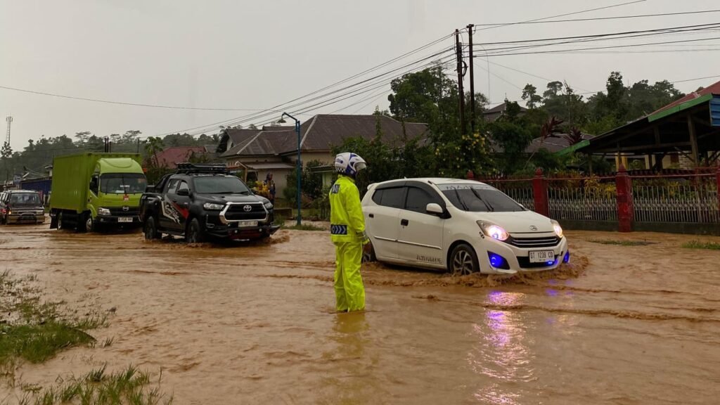 Petugas kepolisian mengatur arus lalu lintas kendaraan yang terjebak banjir di Kecamatan Sampara, Kabupaten Konawe, Sulawesi Tenggara (Sultra).