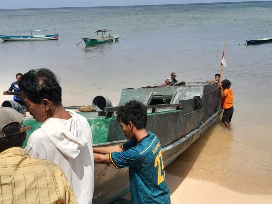 Warga bergotong royong menaikkan kapal yang dibawa Anton dan David di Pantai Huntete, Desa Kulati, Kecamatan Tomia Timur, Kabupaten Wakatobi.
