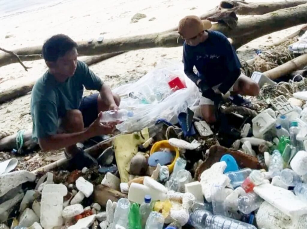 Handik Sol bersama temannya memilah sampah di Pantai Sombu Dive, Desa Sombu, Kecamatan Wangiwangi, Kabupaten Wakatobi.