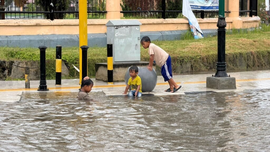 Sejumlah anak mandi hujan saat banjir di perempatan Eks MTQ, Kelurahan Bende, Kecamatan Kadia, Kota Kendari.
