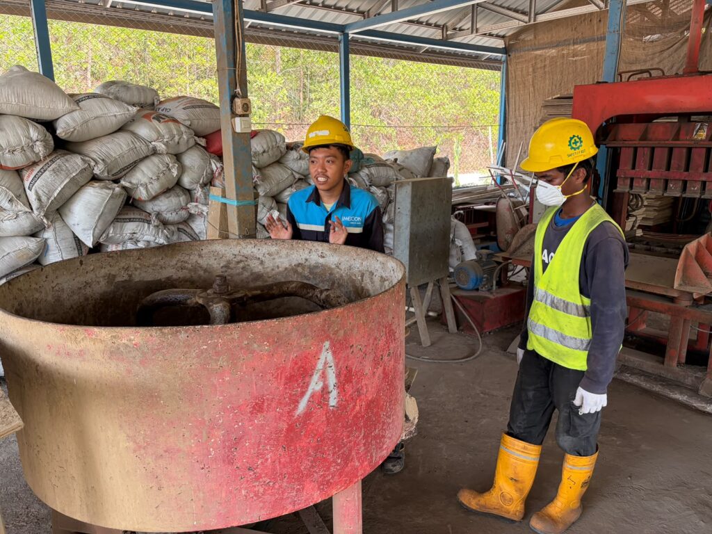 Risal, junior operator di divisi pengolahan FABA DSSP Power Kendari sedang memberikan instruksi kepada pekerja baru untuk mengetahui kegunaan mesin.